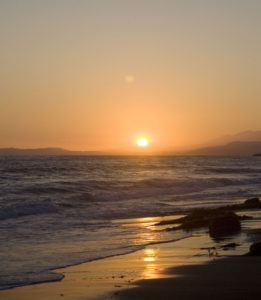 Distant sunset over hills and ocean