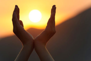 open hands with sun at sunset