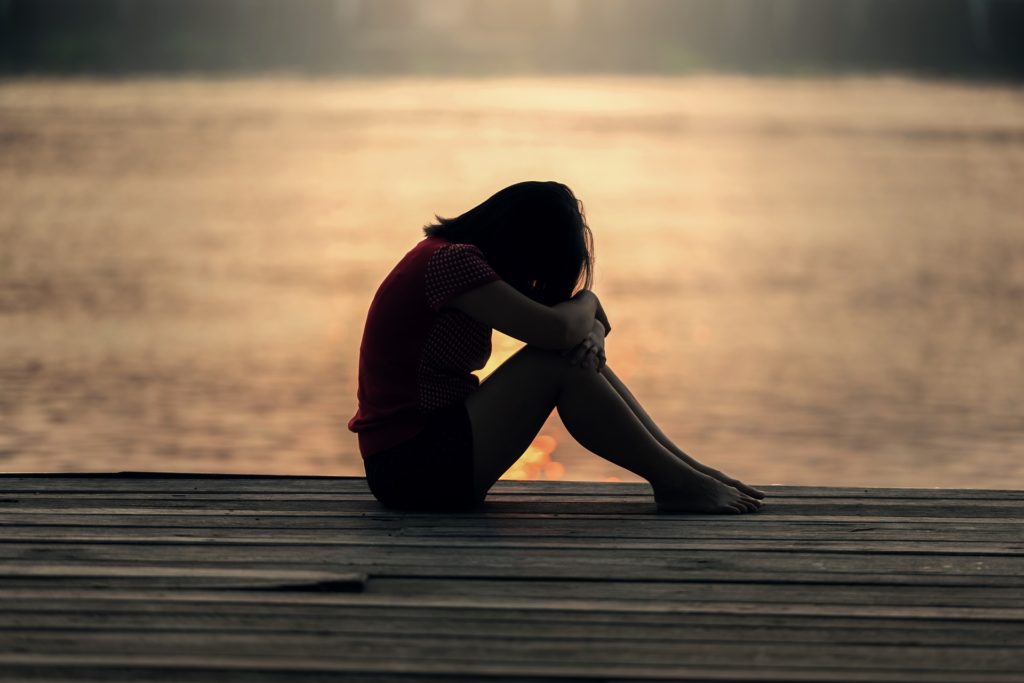 Girl with head in hands on lake jetty sunset Image by Sasin Tipchai from Pixabay