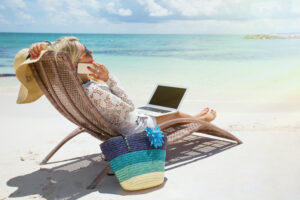woman with laptop relaxing while working on beach